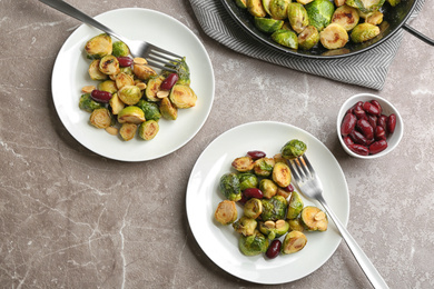 Photo of Delicious roasted brussels sprouts with red beans and peanuts served on grey marble table, flat lay
