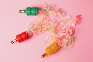 Beautiful serpentine bursting out of small party poppers on pink background, flat lay