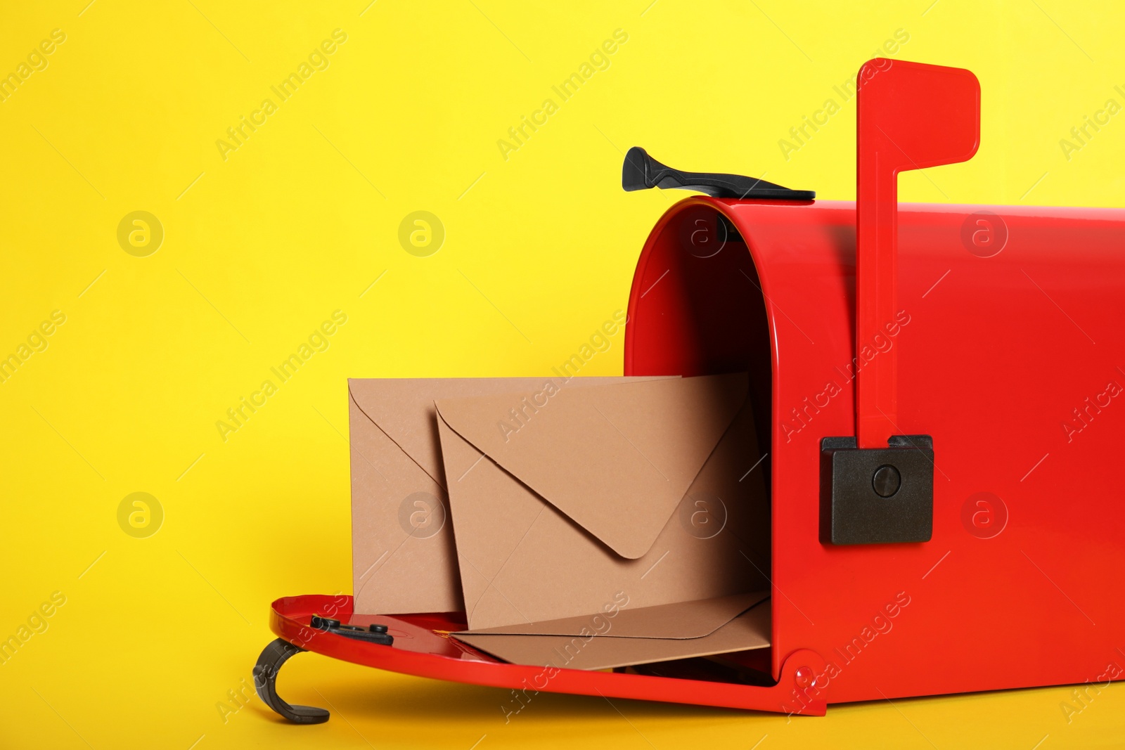 Photo of Open red letter box with envelopes on yellow background, closeup