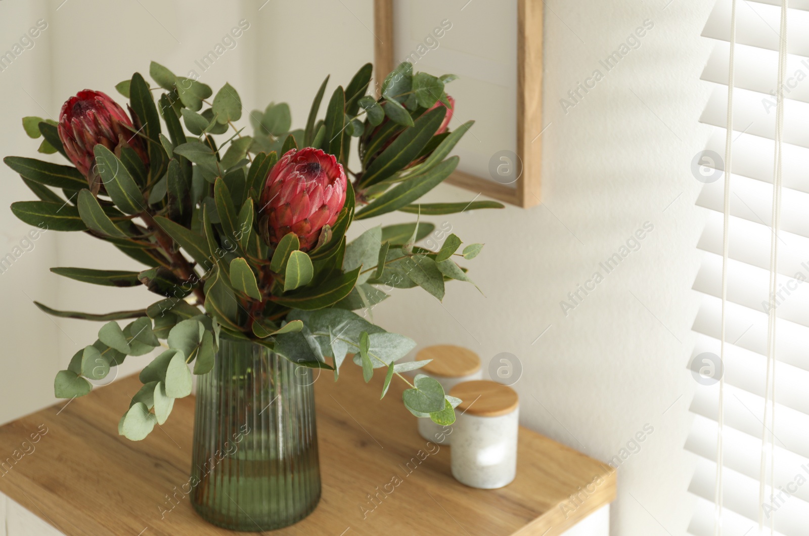 Photo of Vase with beautiful Protea flowers on table indoors