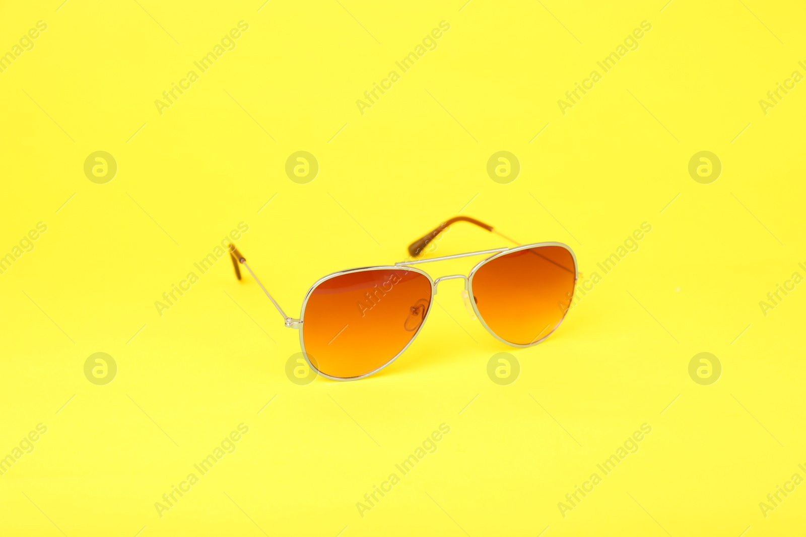 Photo of Stylish pair of sunglasses on yellow background