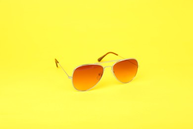 Stylish pair of sunglasses on yellow background