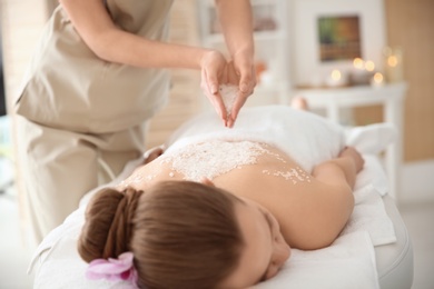 Photo of Beautiful young woman having massage with body scrub in spa salon