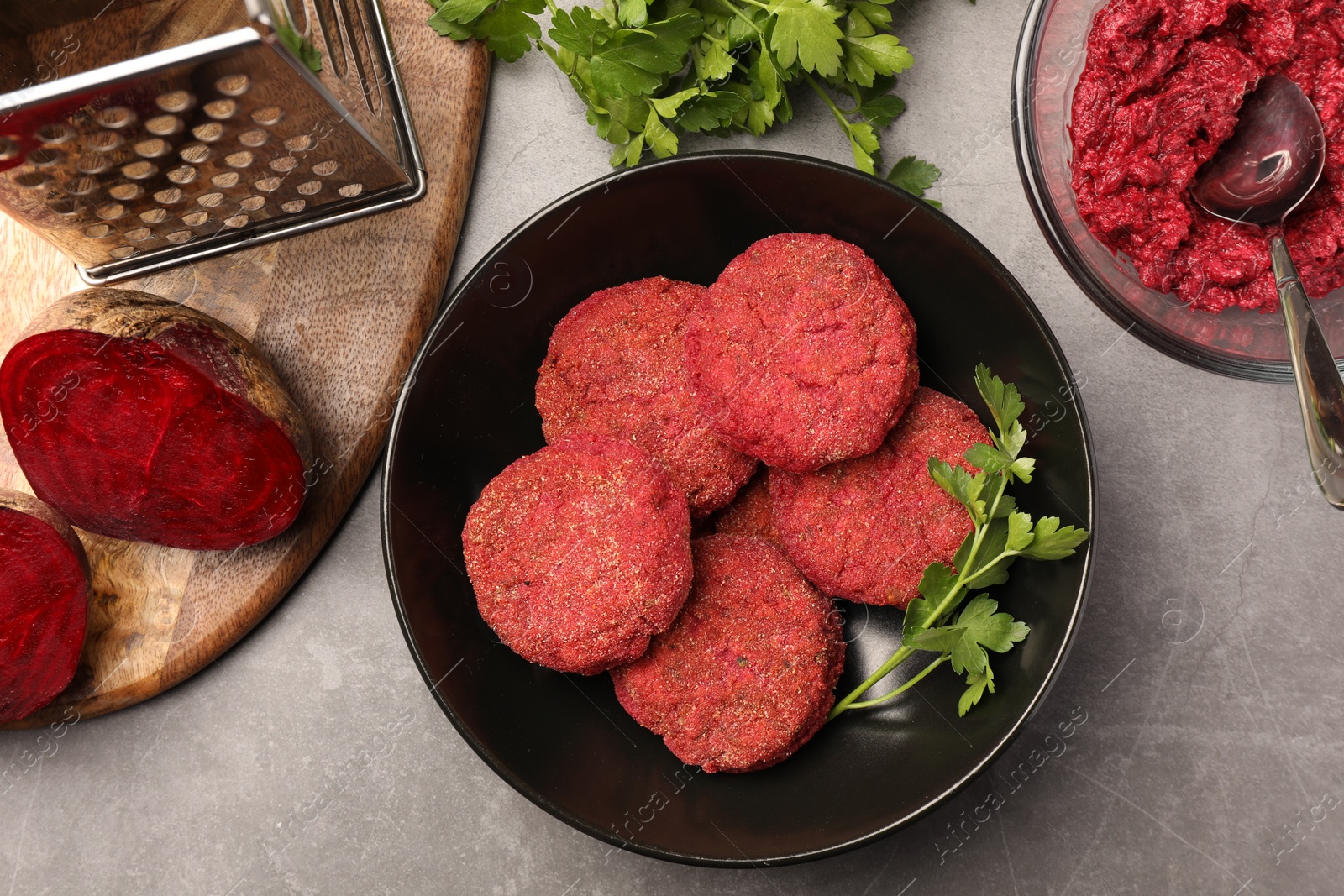 Photo of Delicious beetroot vegan cutlets and ingredients on light gray table, flat lay