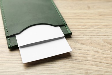 Photo of Leather business card holder with cards on wooden table, closeup. Space for text