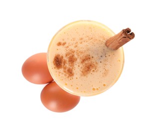 Photo of Delicious eggnog with cinnamon in glass and eggs isolated on white, top view