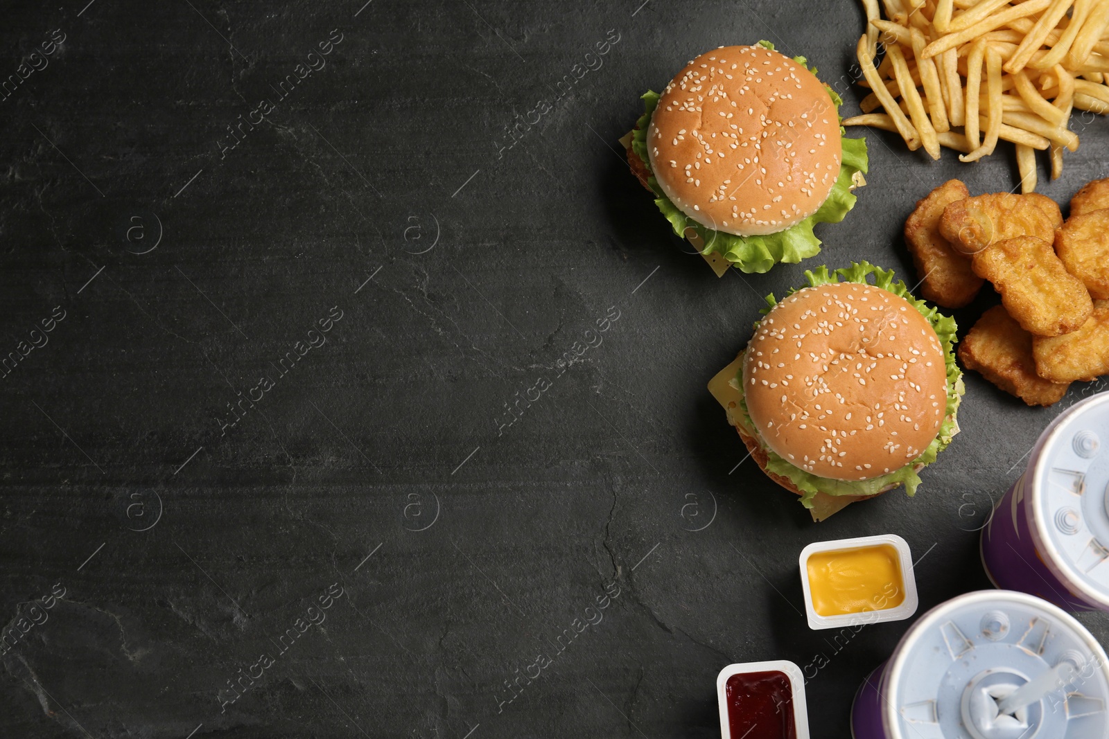 Photo of Flat lay composition with delicious fast food menu on black table. Space for text