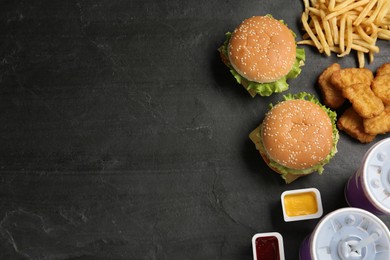 Flat lay composition with delicious fast food menu on black table. Space for text
