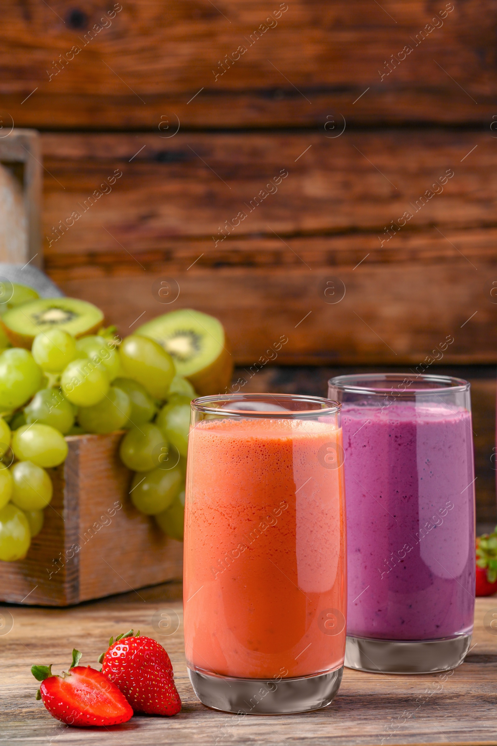 Photo of Glasses with tasty different smoothies and ingredients on wooden table