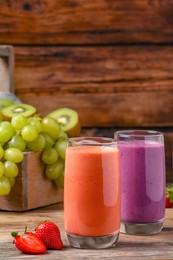 Glasses with tasty different smoothies and ingredients on wooden table