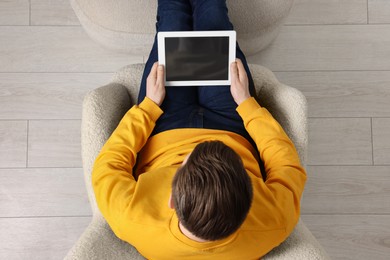 Photo of Man working with tablet in armchair, top view