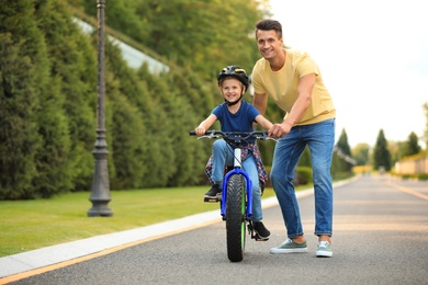 Dad teaching son to ride bicycle outdoors