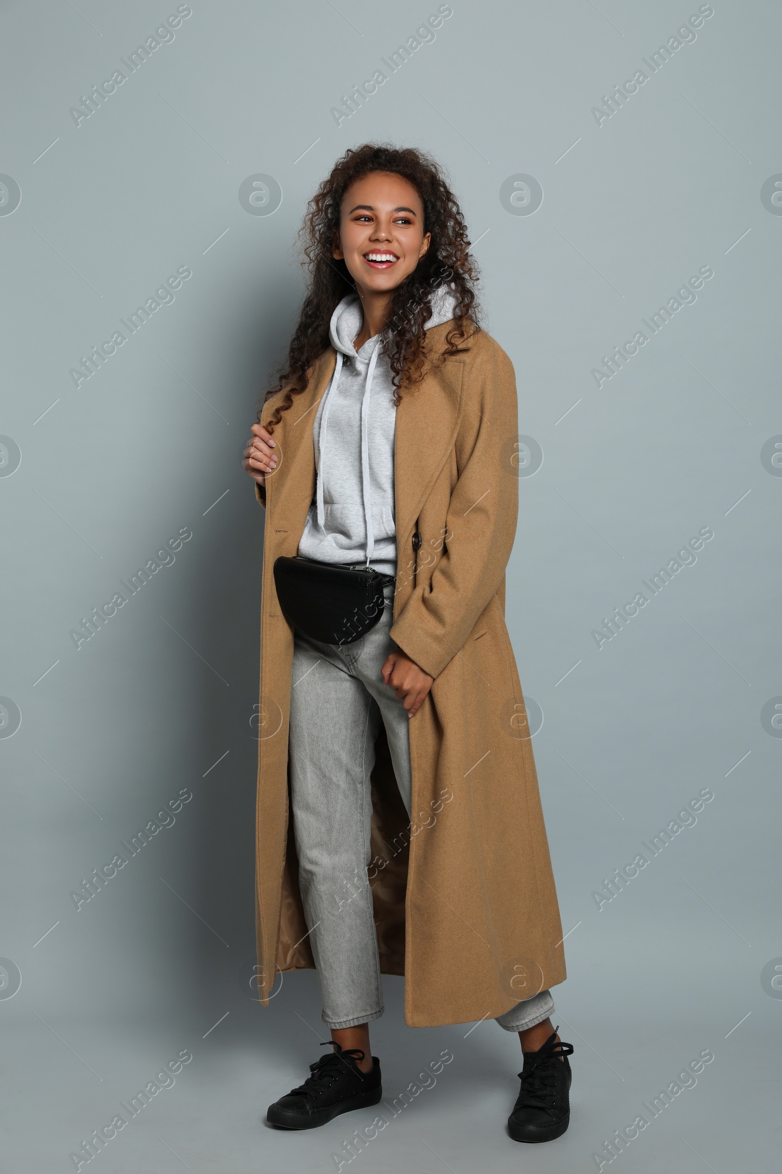 Photo of Beautiful African American woman with stylish waist bag on grey background