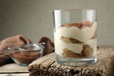 Photo of Delicious tiramisu in glass on wooden table, closeup. Space for text