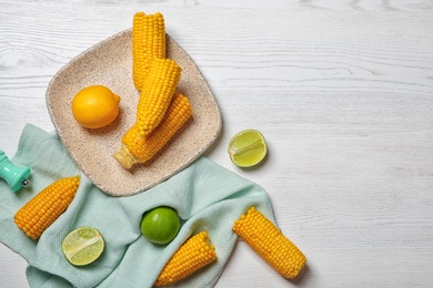 Photo of Flat lay composition with corn cobs and citrus fruits on white wooden background. Space for text