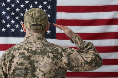 Photo of Soldier in uniform against United states of America flag, back view