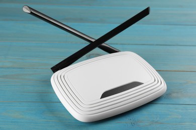 Modern Wi-Fi router on light blue wooden background