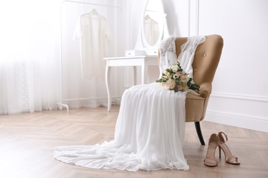 Photo of Elegant wedding dress, shoes and bouquet in room