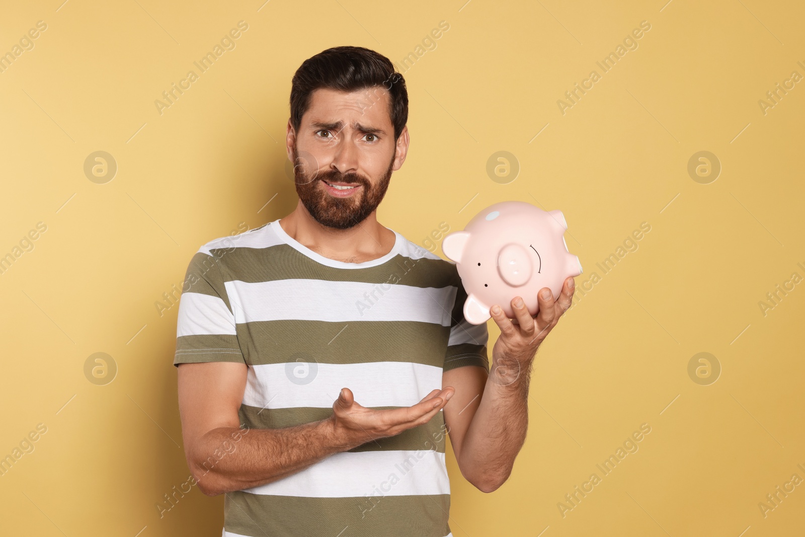 Photo of Man with ceramic piggy bank on beige background