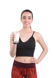 Beautiful young woman in sportswear drinking milk on white background