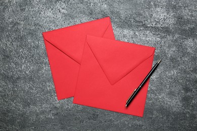 Photo of Red envelopes and pen on grey table, top view