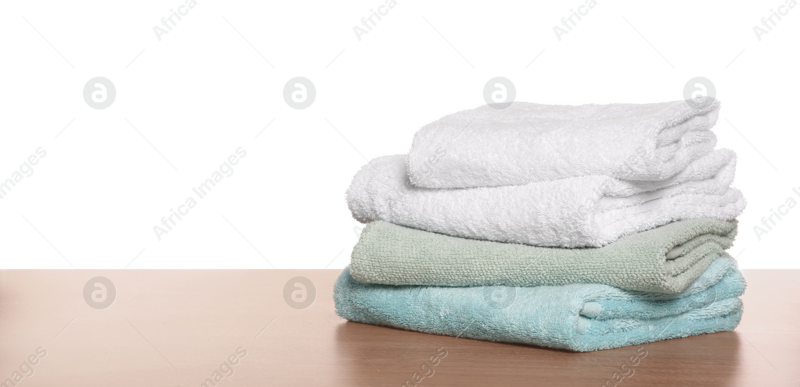 Photo of Soft colorful terry towels on wooden table against white background, space for text