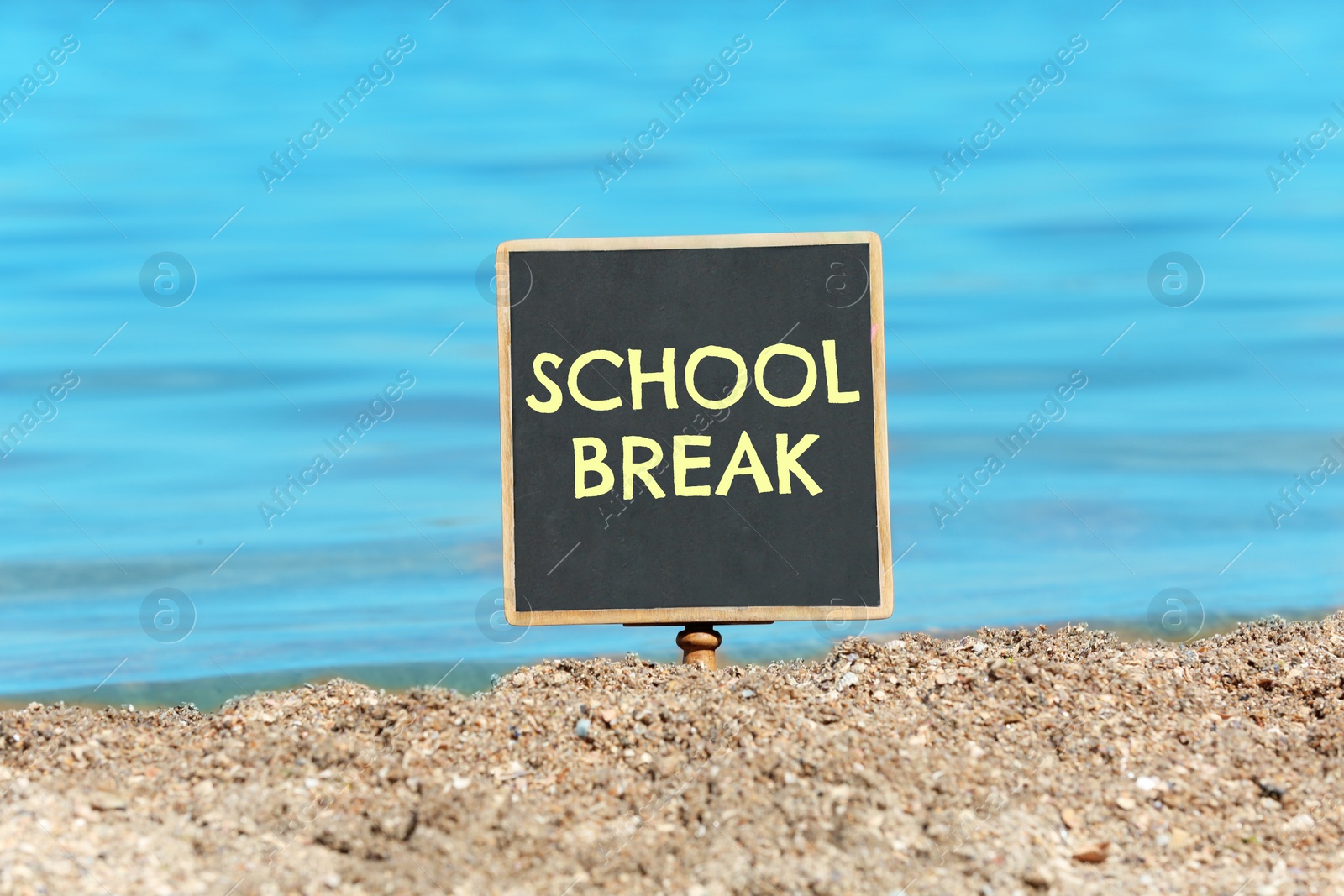 Image of Small black chalkboard with text School Break on beach. Seasonal holidays 