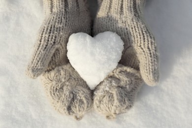 Photo of Woman holding heart shaped snowball outdoors, top view