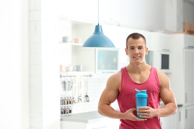Photo of Athletic young man with protein shake in kitchen
