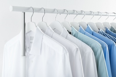 Photo of Men's clothes hanging on wardrobe rack against white background