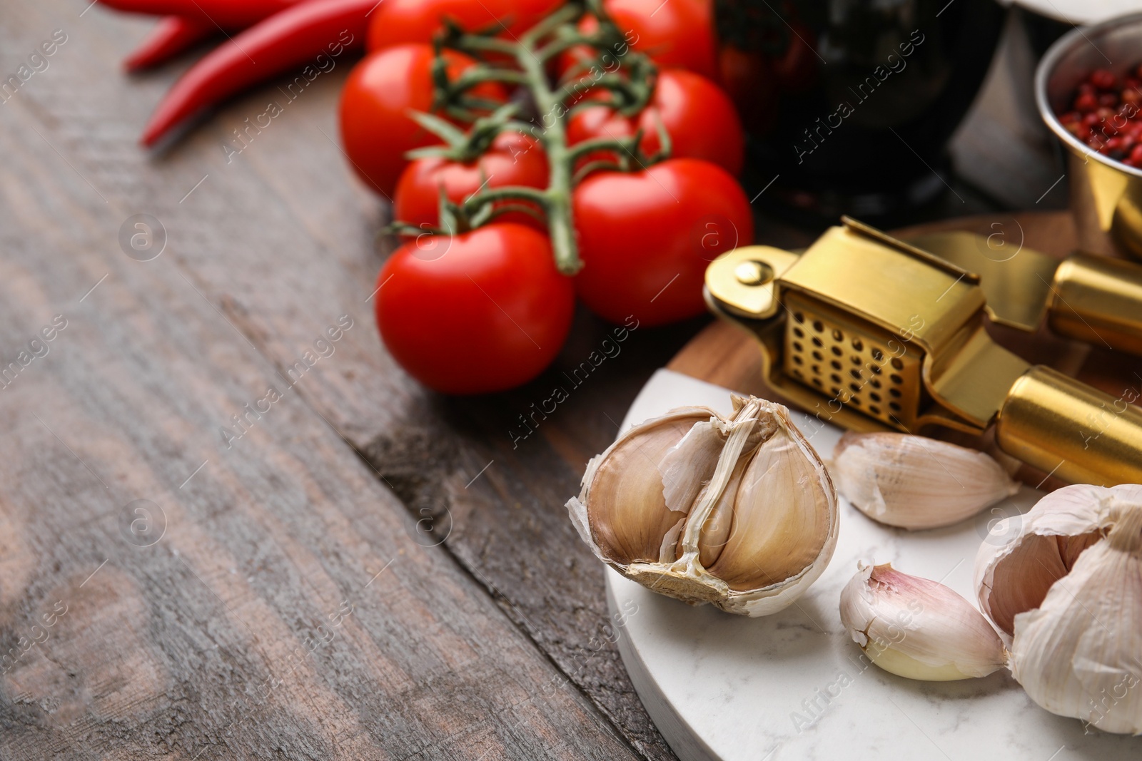 Photo of Different fresh ingredients for marinade and garlic press on wooden table, closeup. Space for text