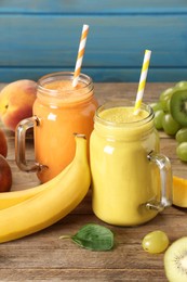 Mason jars of different tasty smoothies and fresh ingredients on wooden table