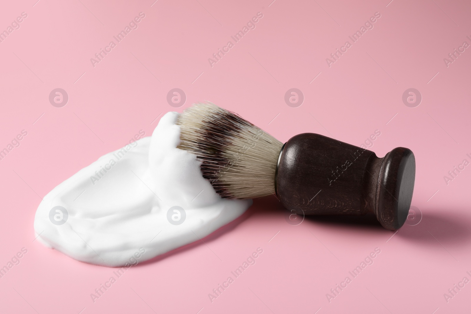 Photo of Brush with shaving foam on pink background, closeup