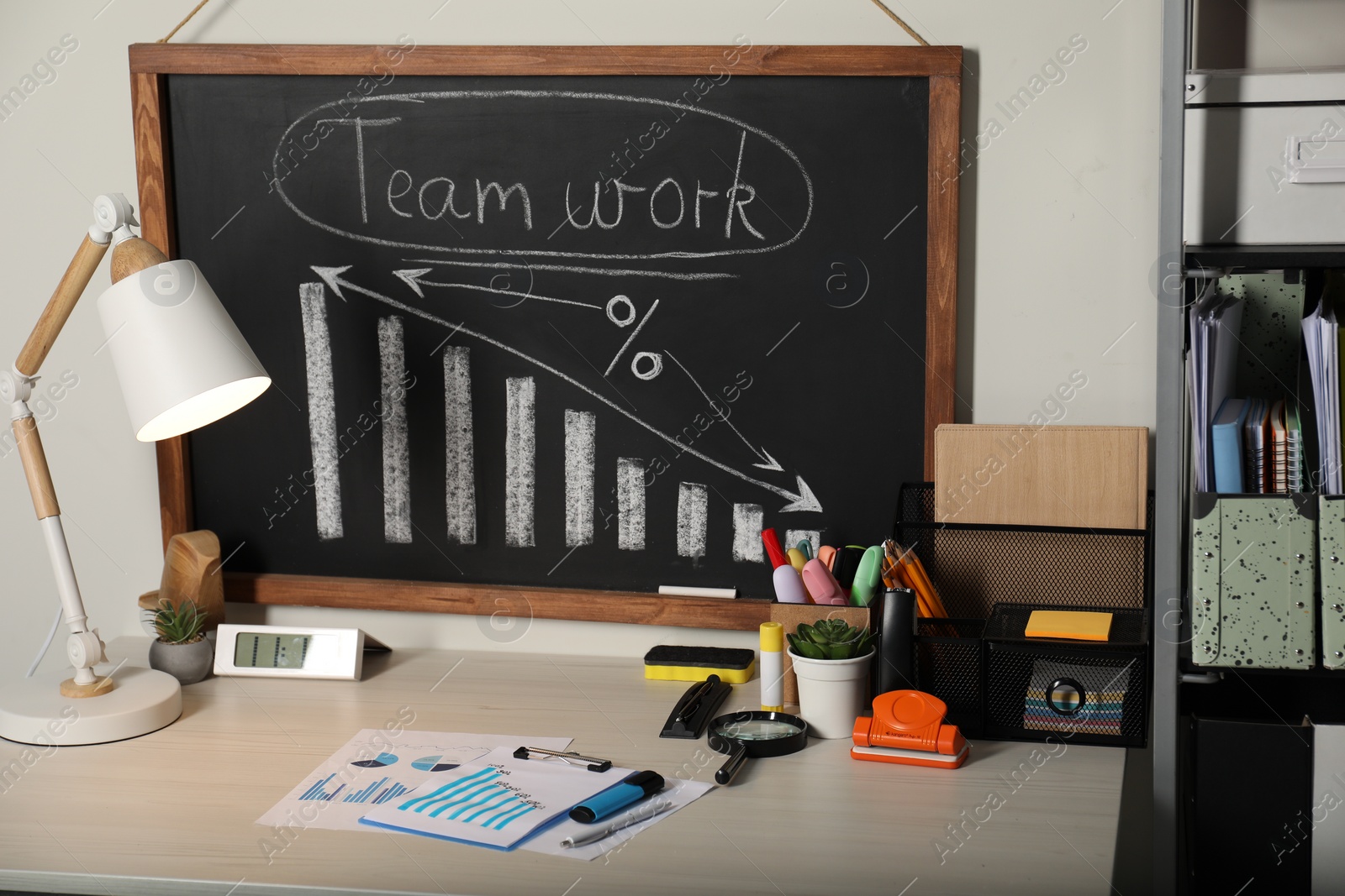 Photo of Business process planning and optimization. Workplace with lamp, blackboard, graphs and other stationery on wooden table