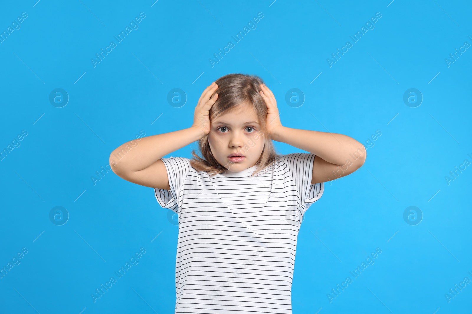 Photo of Worried little girl on light blue background