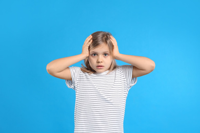 Photo of Worried little girl on light blue background