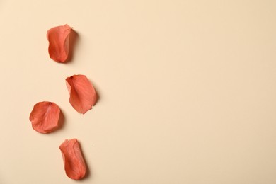 Photo of Red rose petals on beige background, flat lay. Space for text