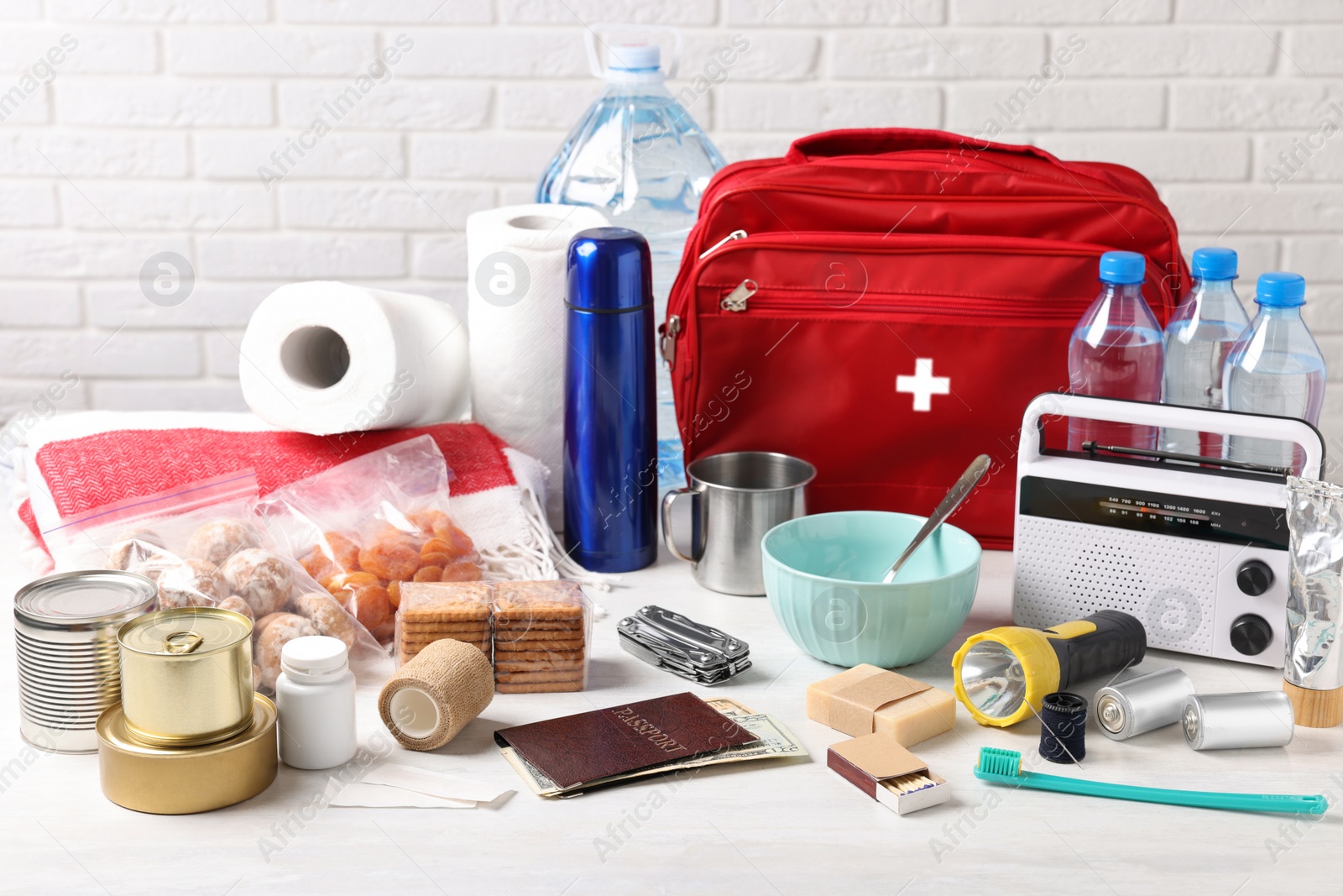 Photo of Disaster supply kit for earthquake on white wooden table near brick wall