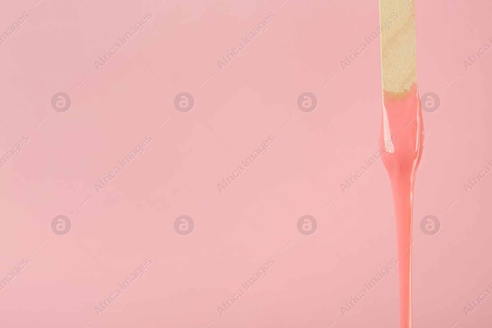 Photo of Wooden spatula with hot depilatory wax on pink background. Space for text
