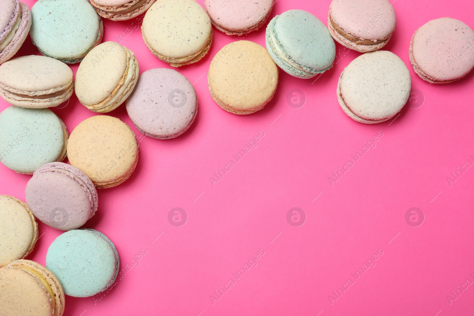 Photo of Delicious colorful macarons on pink background, flat lay. Space for text