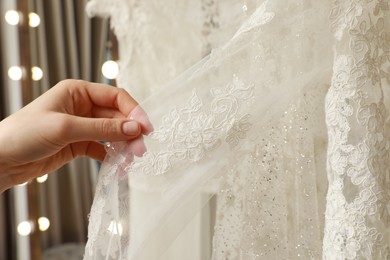 Photo of Young woman choosing wedding dress in salon, closeup