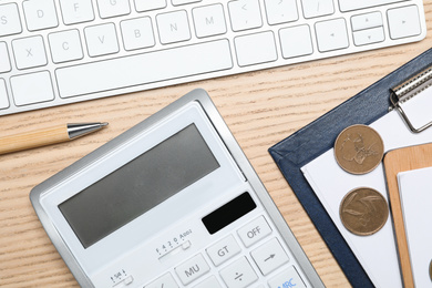 Photo of Calculator, money, keyboard and stationery on wooden table, flat lay. Tax accounting