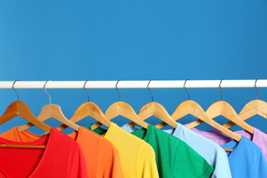 Photo of Bright clothes on blue background, space for text. Rainbow colors