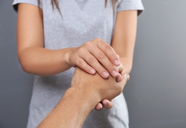 Photo of Woman holding man's hand on gray background, closeup. Concept of support and help