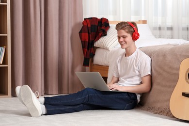 Photo of Online learning. Smiling teenage boy typing on laptop at home