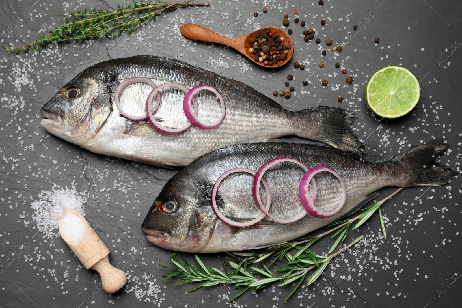 Photo of Flat lay composition with fresh raw dorado fish and ingredients on black table