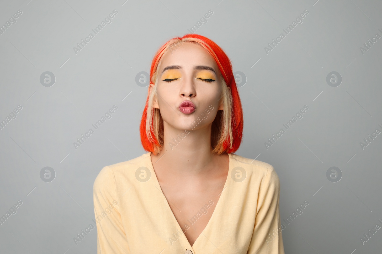 Photo of Beautiful young woman with bright dyed hair on light grey background