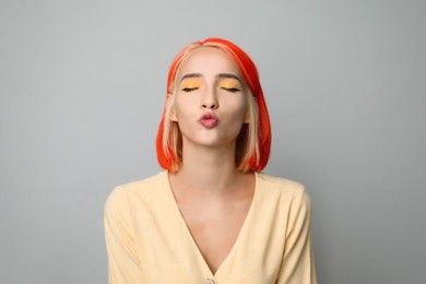 Beautiful young woman with bright dyed hair on light grey background