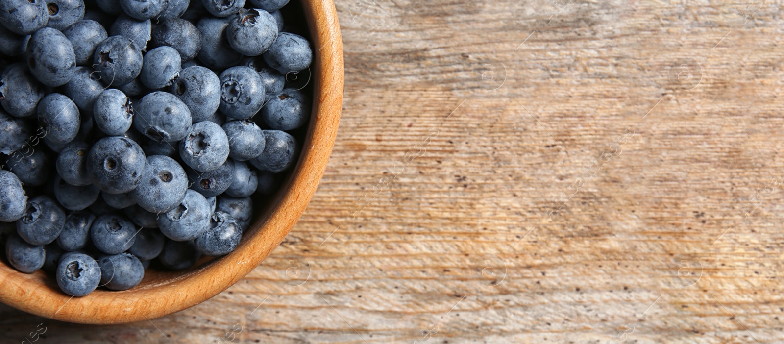 Image of Tasty fresh blueberries on wooden table, top view with space for text. Banner design