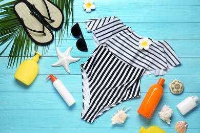 Photo of Flat lay composition with striped swimsuit and beach accessories on blue wooden background